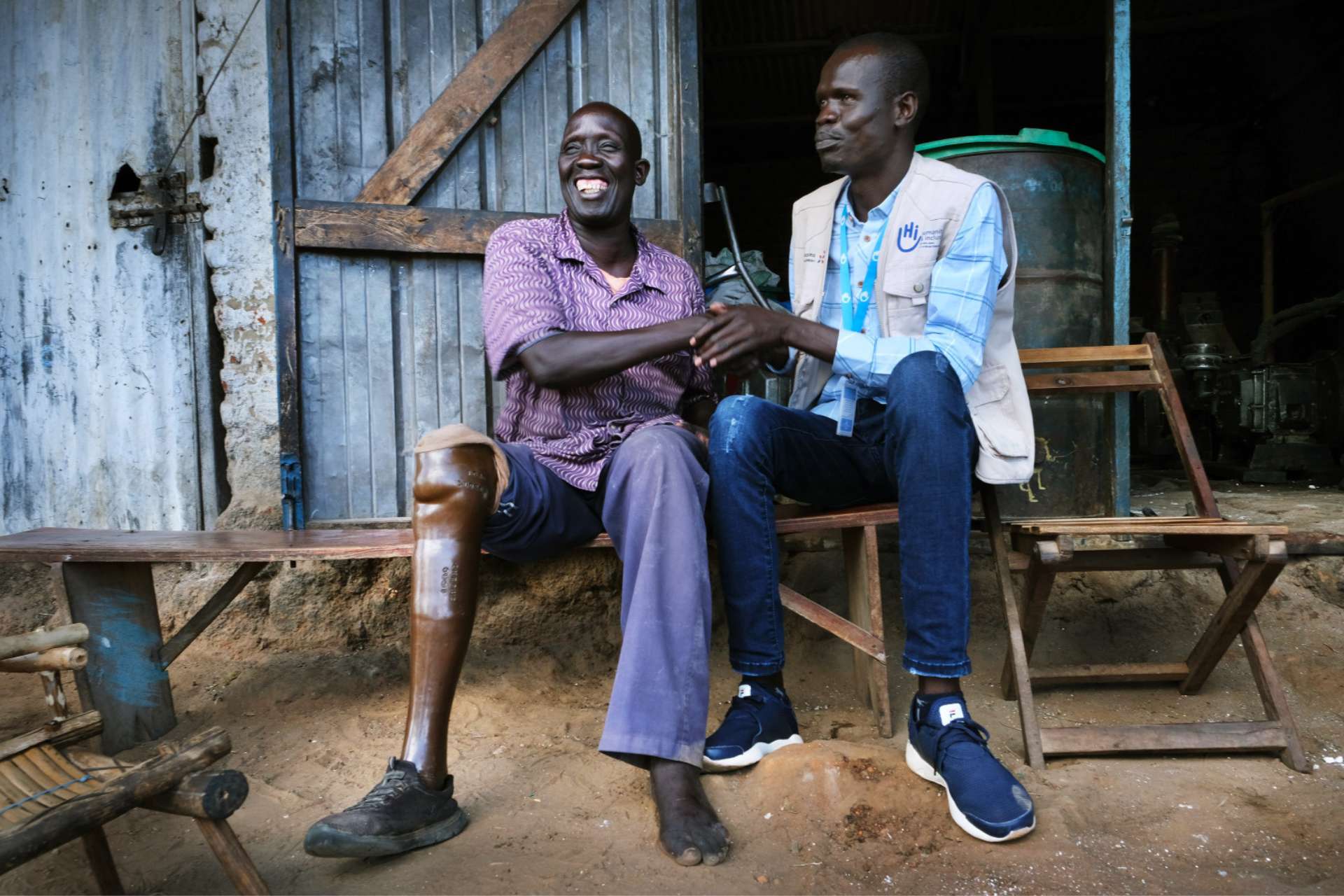Oliver mit einem Helfer von Handicap International, beide lachen ausgelassen.